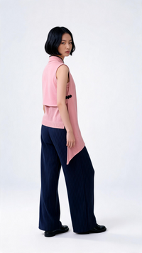 Woman wearing a pink sleeveless top and navy pants on a white background