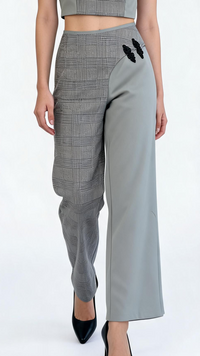 Woman wearing a gray checkered outfit with a high collar and wide-leg pants on a white background